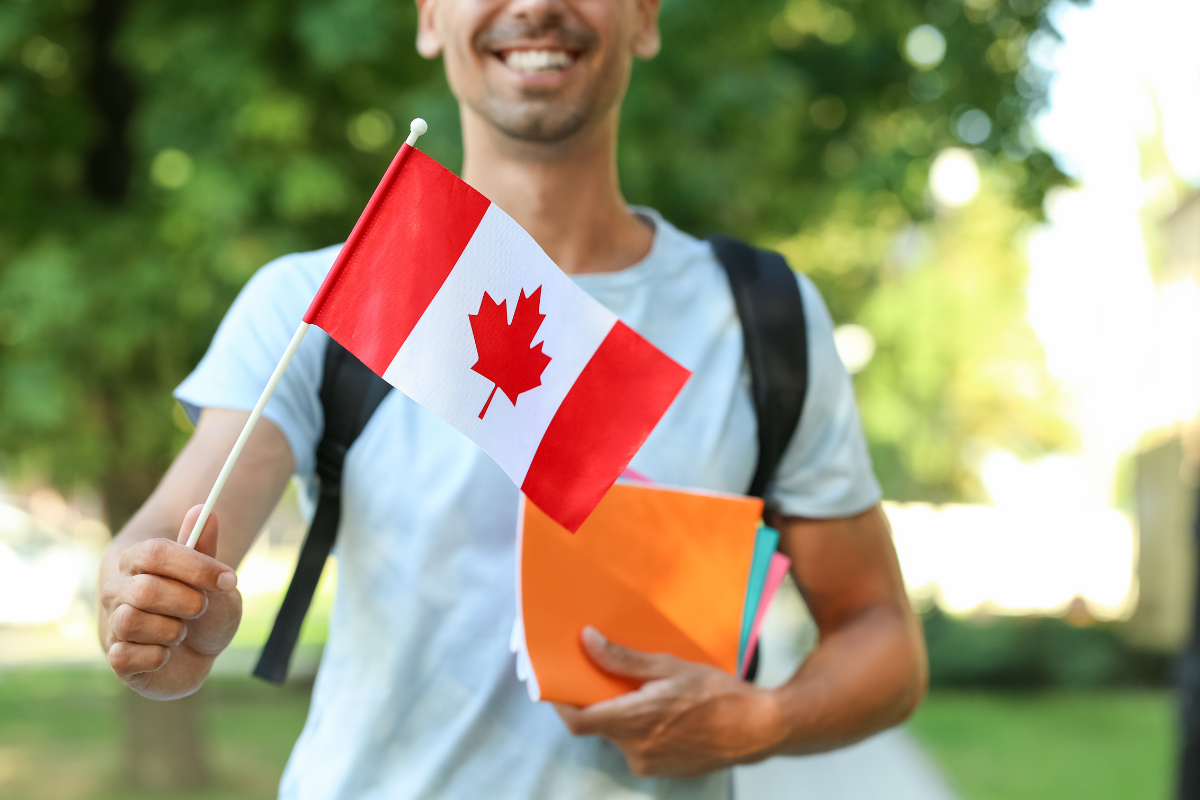 an International Student holding Notebooks and Canadian Flag